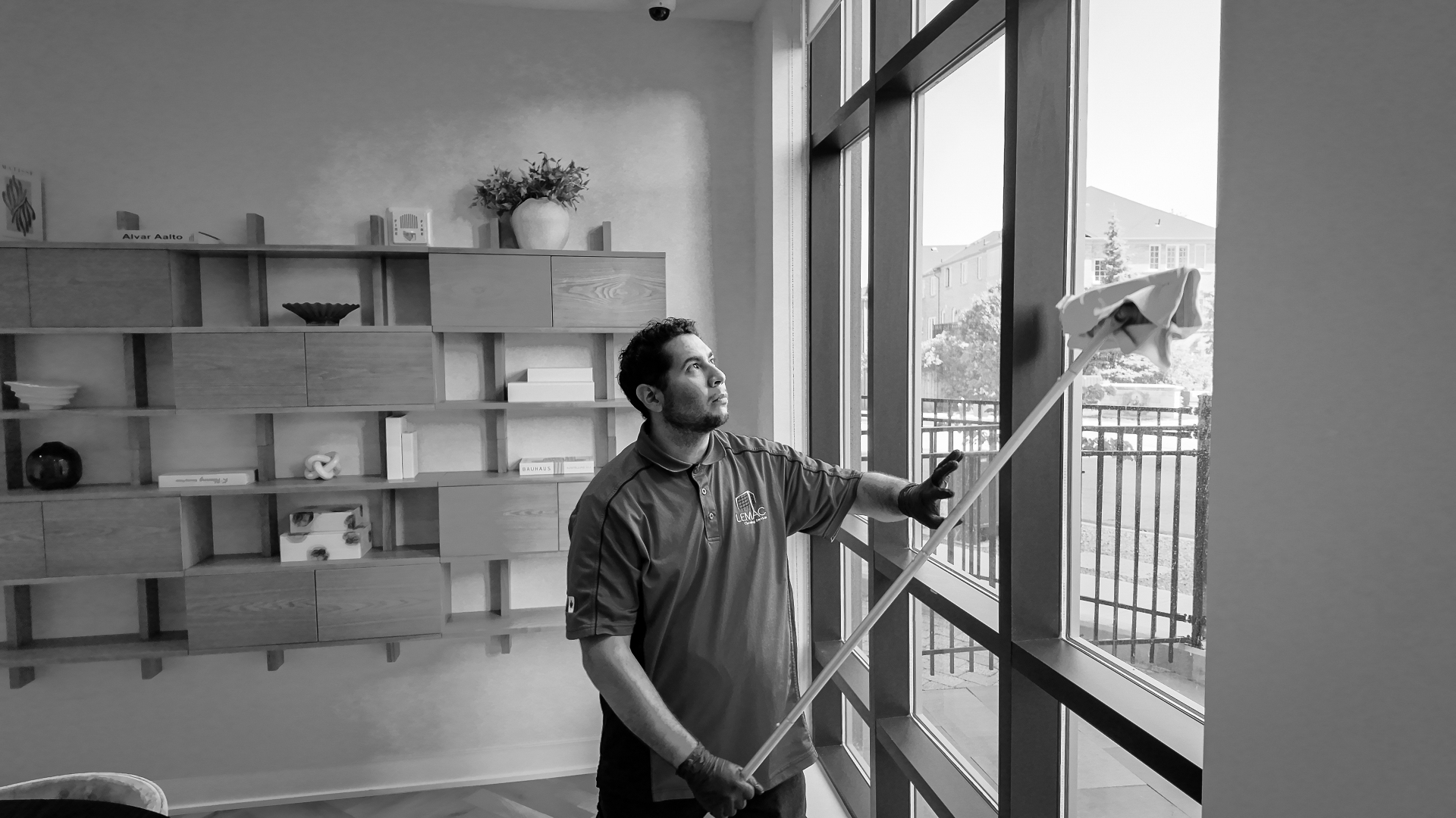 LEMAC team member cleaning a floor-to-ceiling window in a modern interior